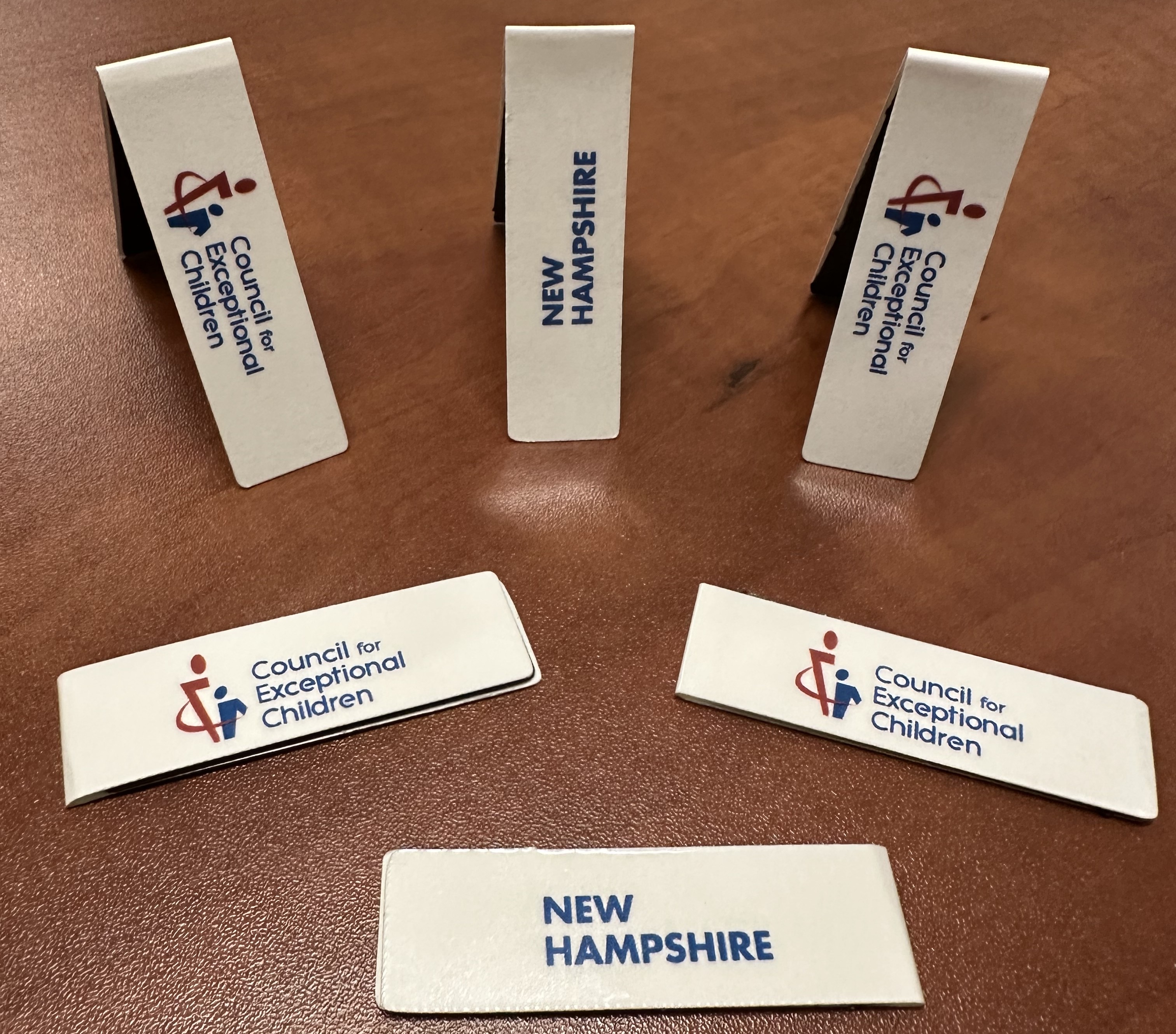Photo of a table top with a collection of 6 bookmarks on display, each with the CEC New Hampshire logo